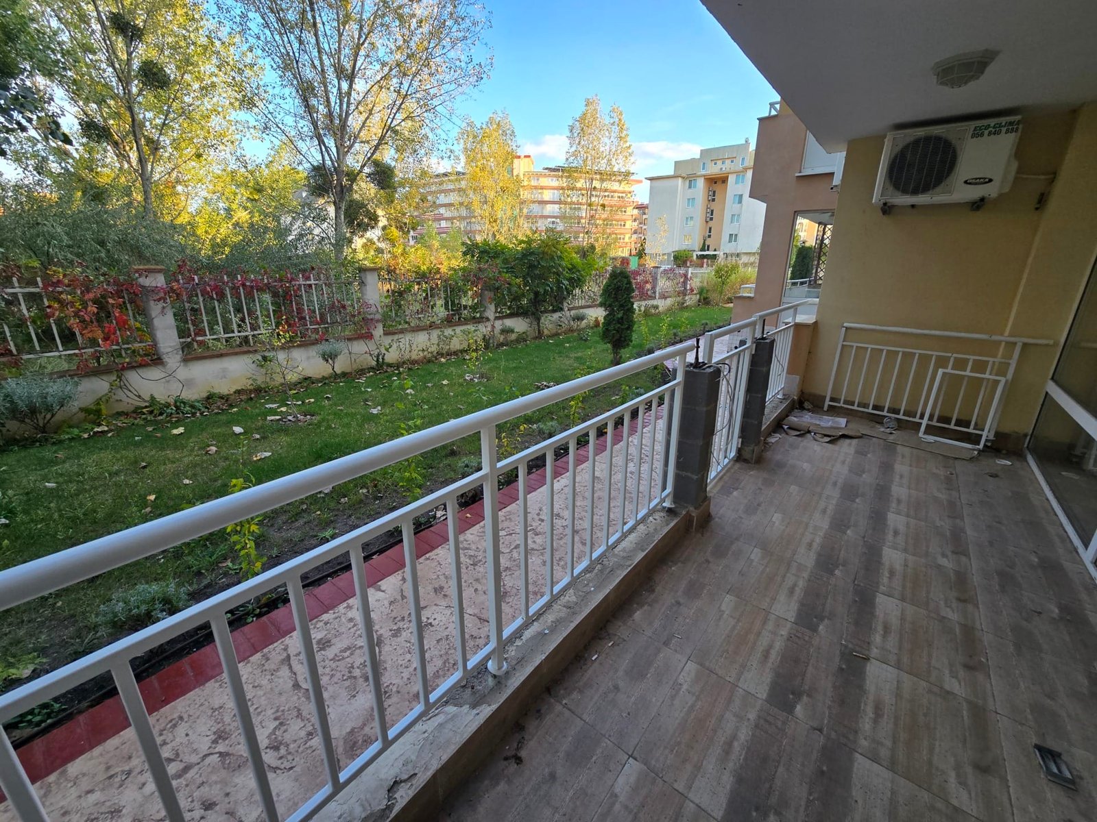 Балкон с видом на зелёный сад в Болгарии, уютное место для отдыха и наслаждения природой рядом с жилыми комплексами.