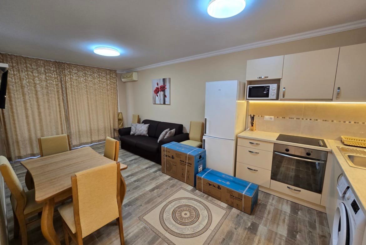 Современная кухня-гостиная в Болгарии с новыми мебелью и бытовой техникой, готовая к продаже. Коробки и стол создают уют.