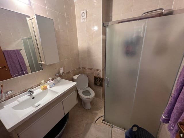 Современная ванная комната с душевой кабиной, унитазом и раковиной, оформленная в светлых тонах, идеально подходит для отдыха в Болгарии.