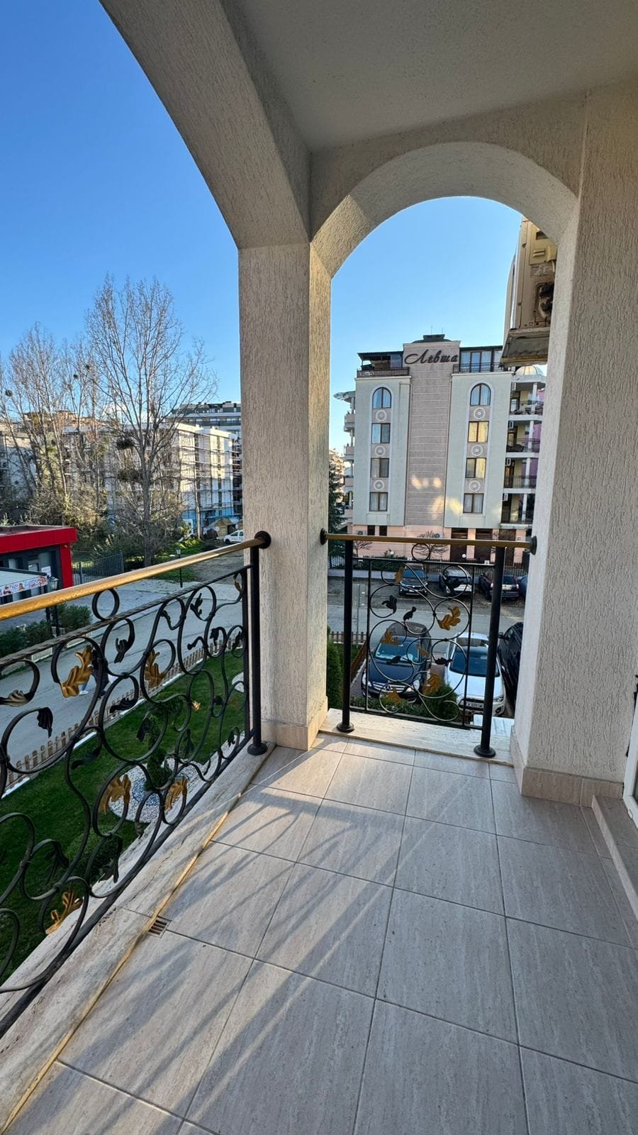 Балкон с металлическим ограждением, вид на улицу и здания, идеальное место для продажи недвижимости в Болгарии.