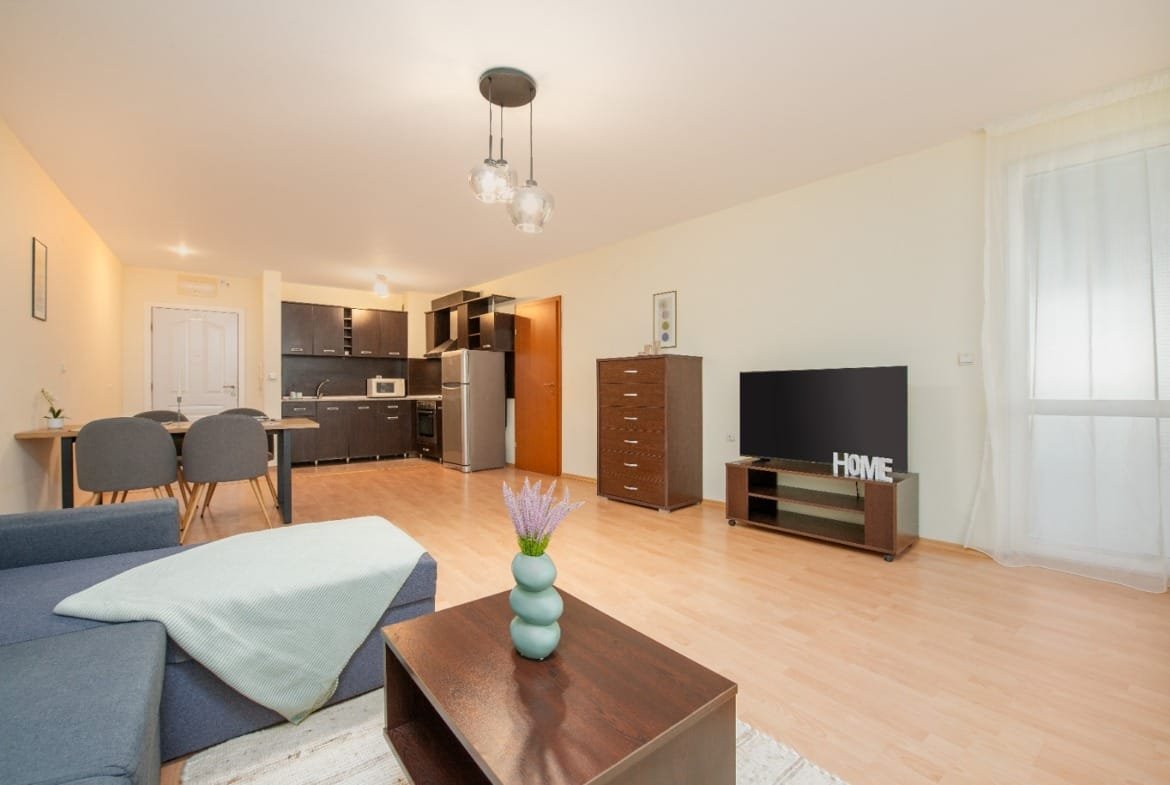 Современная квартира в Болгарии с уютной гостиной, кухней и телевизором, идеальна для проживания или аренды.