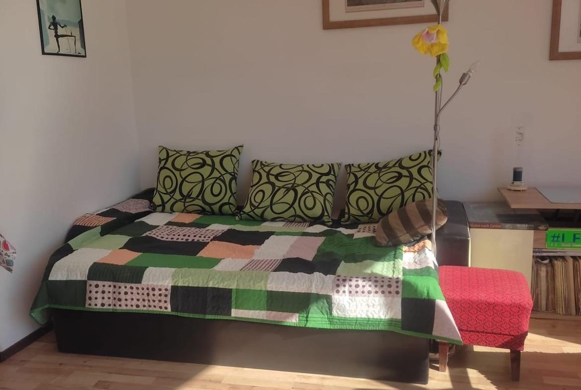 Современный интерьер квартиры в Болгарии с диваном, яркими подушками и деревянным полом, идеально подходящий для продажи.