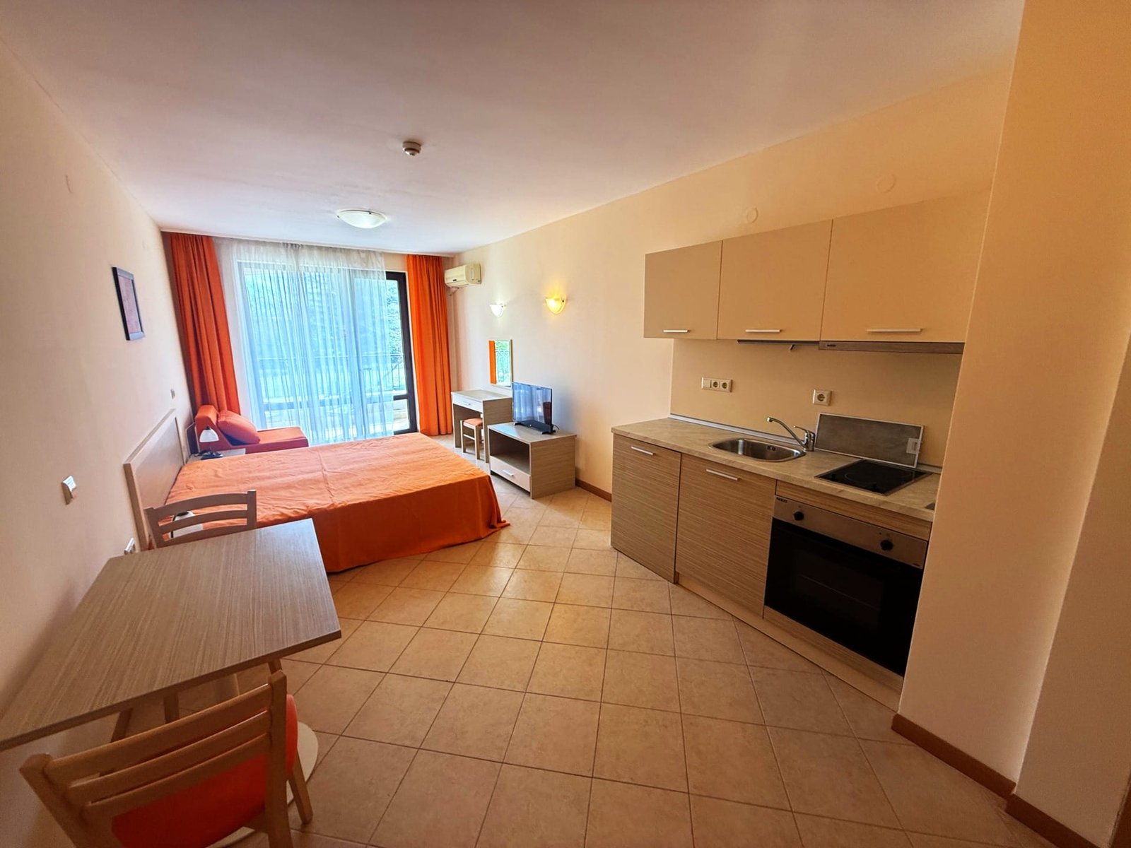 Современная однокомнатная квартира с кухонным уголком и обеденной зоной, балкон с выходом на светлую гостиую в Болгарии.