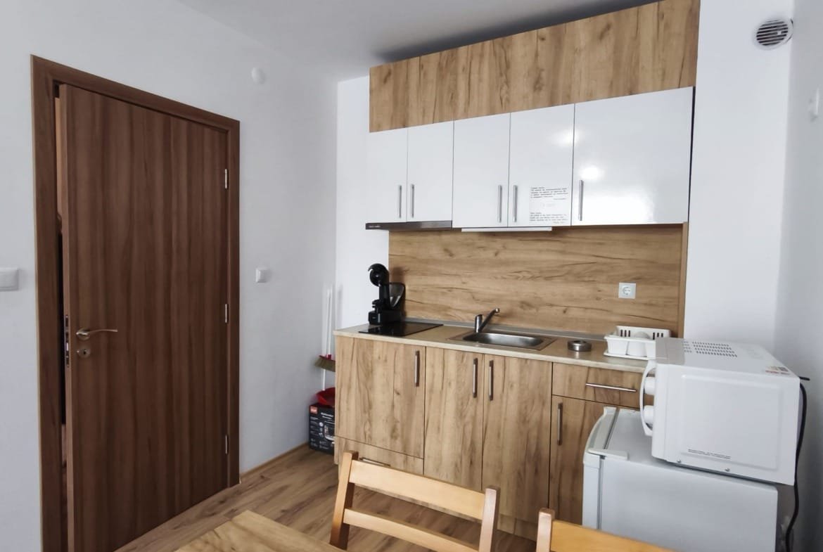 Современная кухня с деревянными фасадами, встроенной техникой и обеденным столом, идеальная для продажи недвижимости в Болгарии.