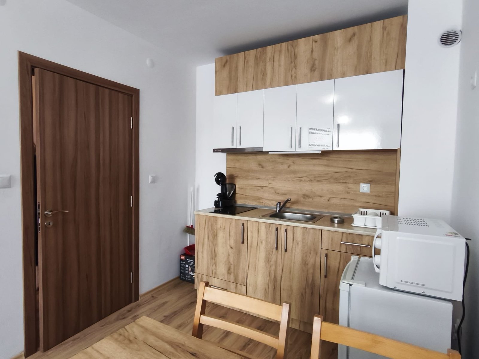 Современная кухня с деревянными фасадами и бытовой техникой Современная кухня с деревянными фасадами, встроенной техникой и обеденным столом, идеальная для продажи недвижимости в Болгарии.