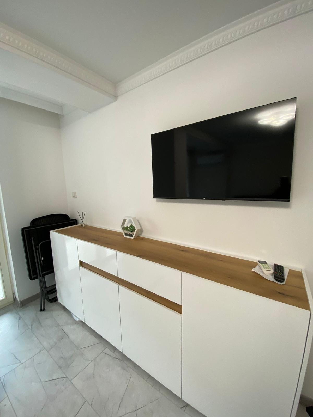 Современный интерьер квартиры в Болгарии с белым стендом и телевизором на стене, подходящим для сдачи в аренду.