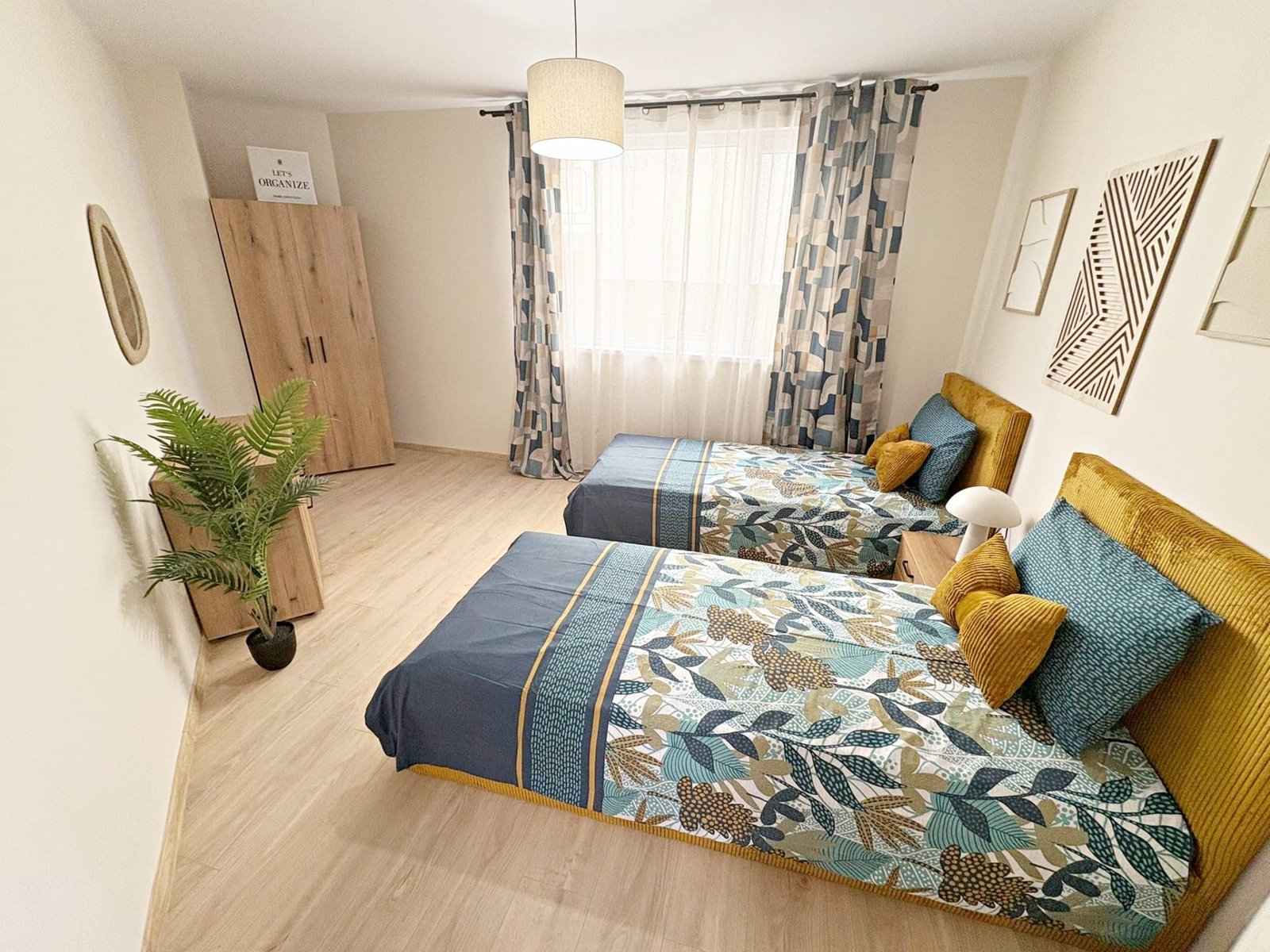 Две кровати с яркими покрывалами, современный интерьер спальни и уютное освещение, идеальные для покупки недвижимости в Болгарии.