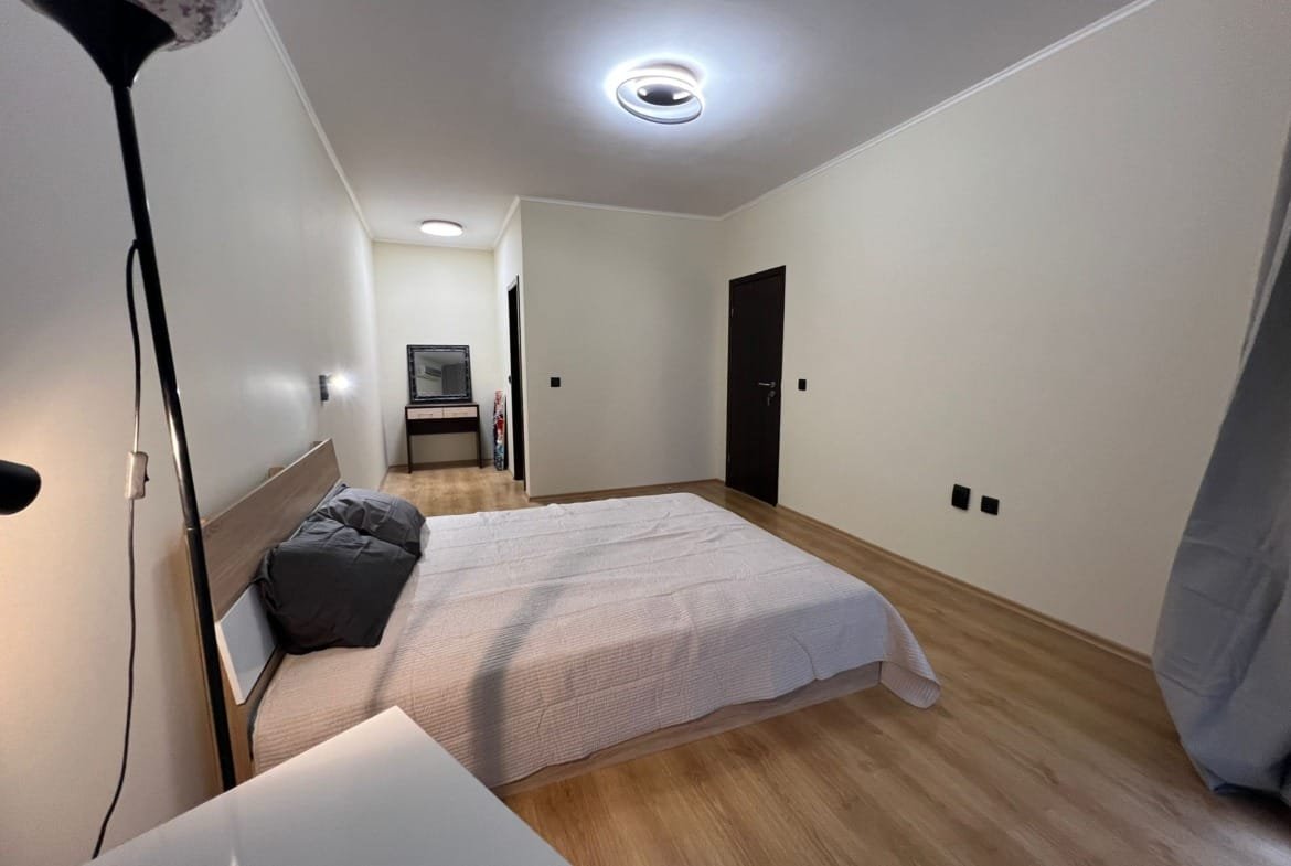 Современная спальня с двуспальной кроватью и уютным интерьером, идеальная для покупки недвижимости в Болгарии.