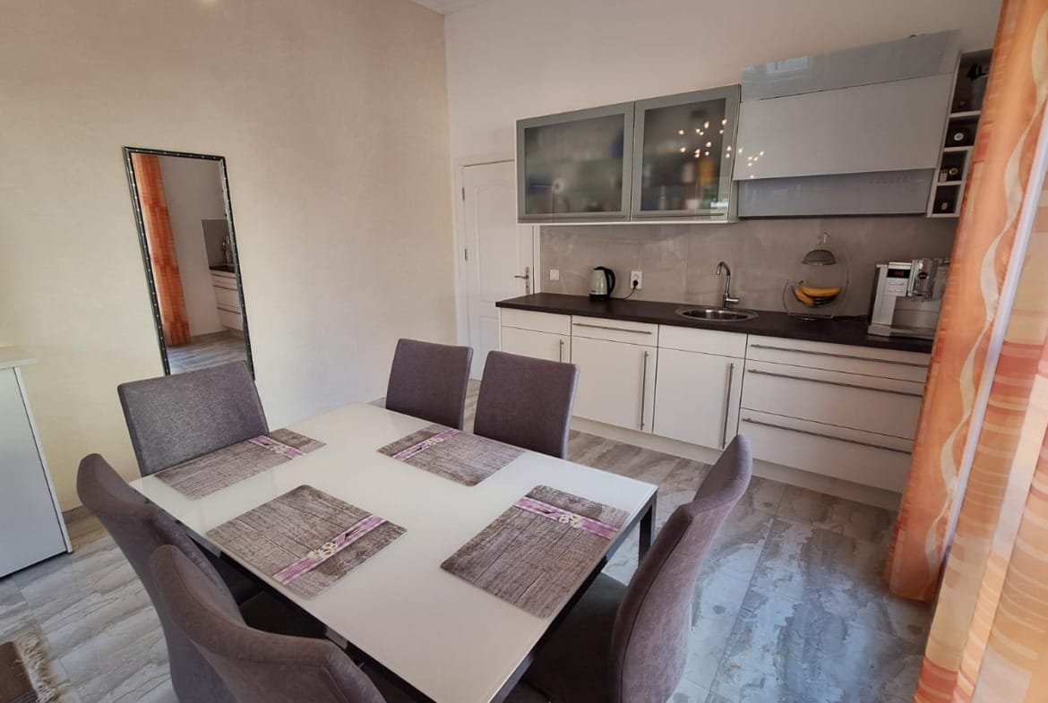 Современная кухня-студия в Болгарии с обеденным столом, серыми стульями и стильной бытовой техникой. Идеально для комфортной жизни.