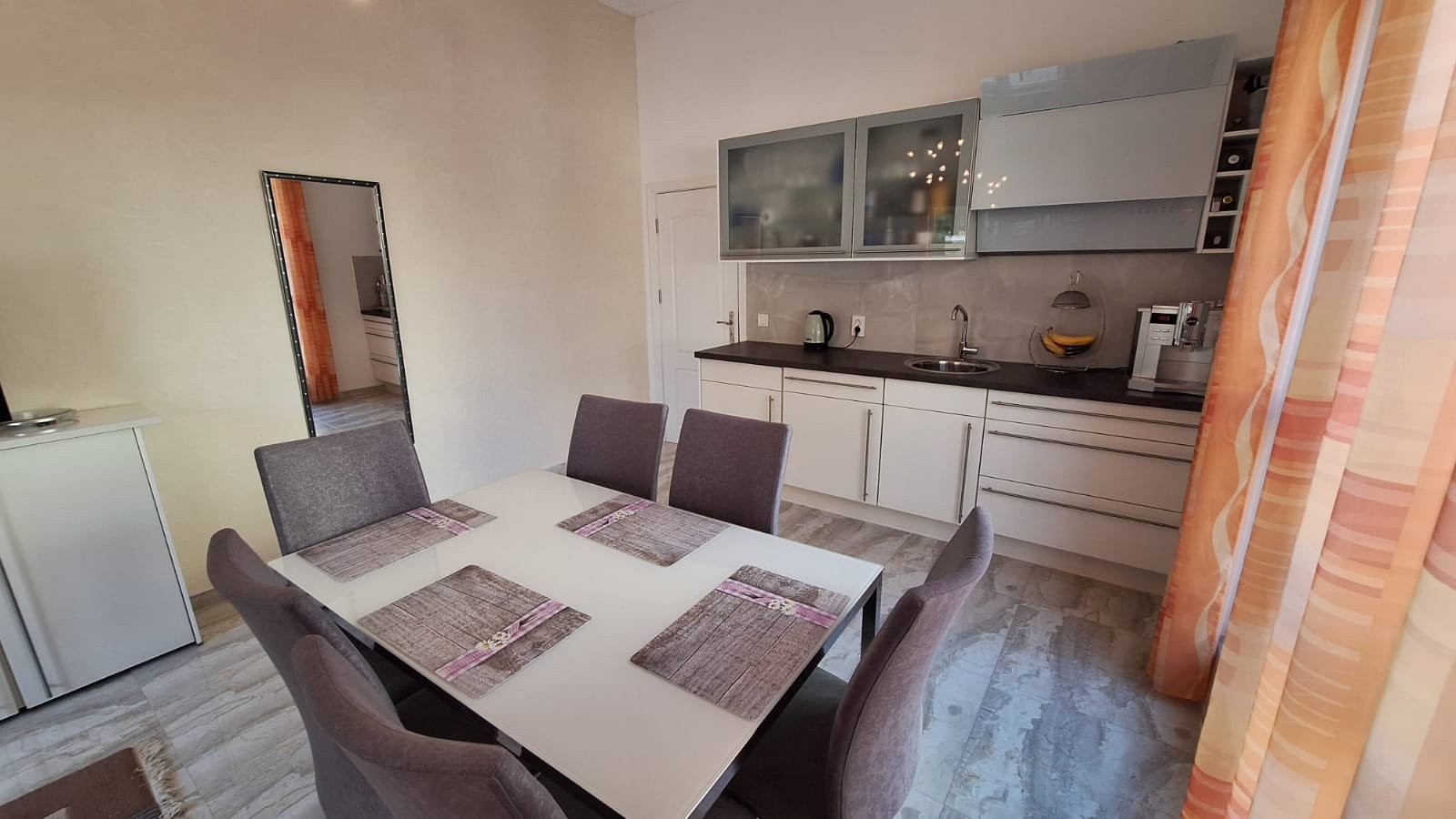 Современная кухня-студия в Болгарии с обеденным столом, серыми стульями и стильной бытовой техникой. Идеально для комфортной жизни.