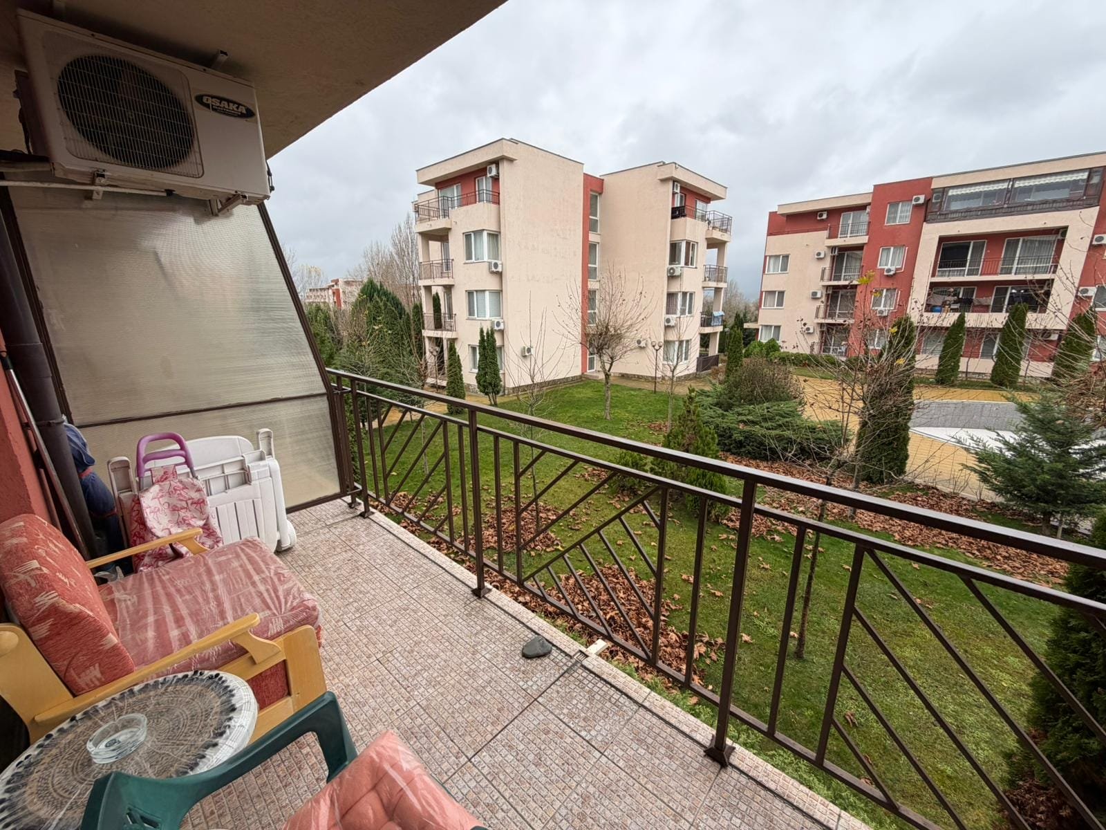 Балкон с видом на жилой комплекс и зеленые насаждения Балкон с видом на зеленую территорию и многоквартирные дома в Болгарии, комфортное место для отдыха и покупки недвижимости.