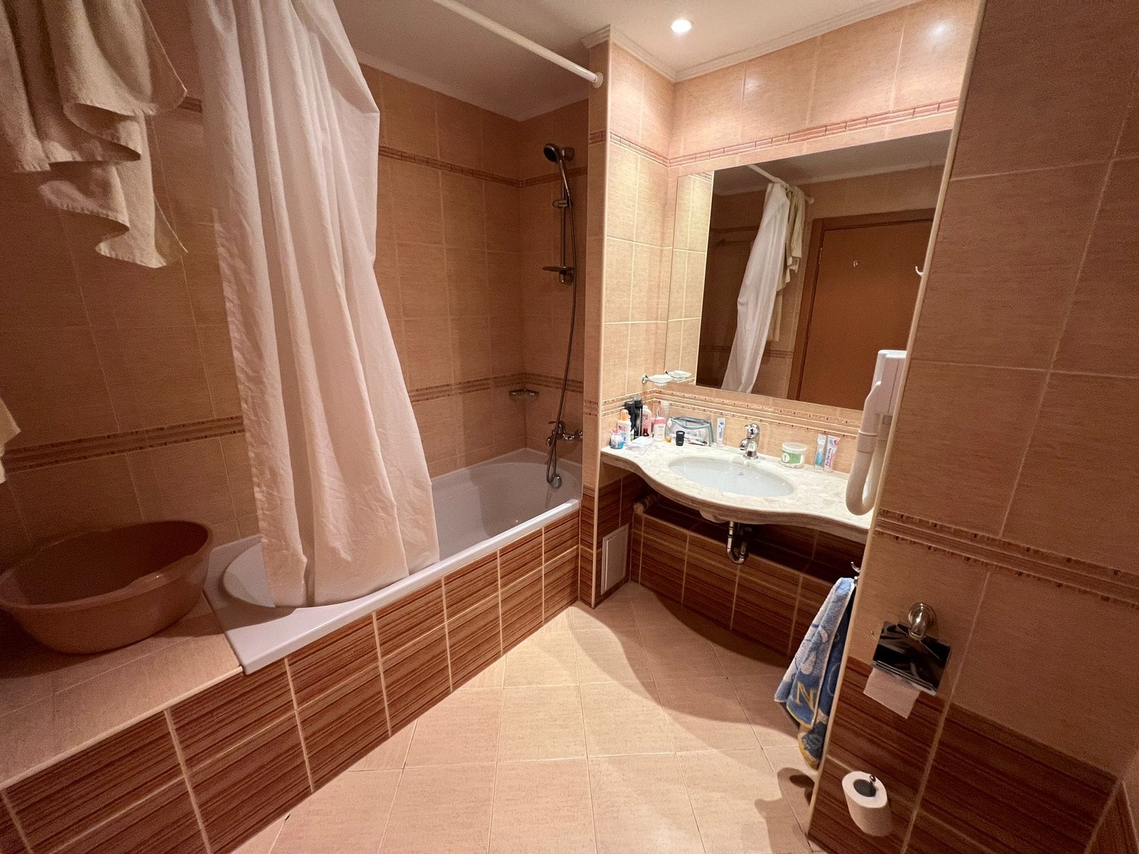 Современная ванная комната с ванной и зеркалом. Современная ванная комната с ванной, раковиной и зеркалом, отделанная плиткой в светлых тонах, удобная для жизни в Болгарии.