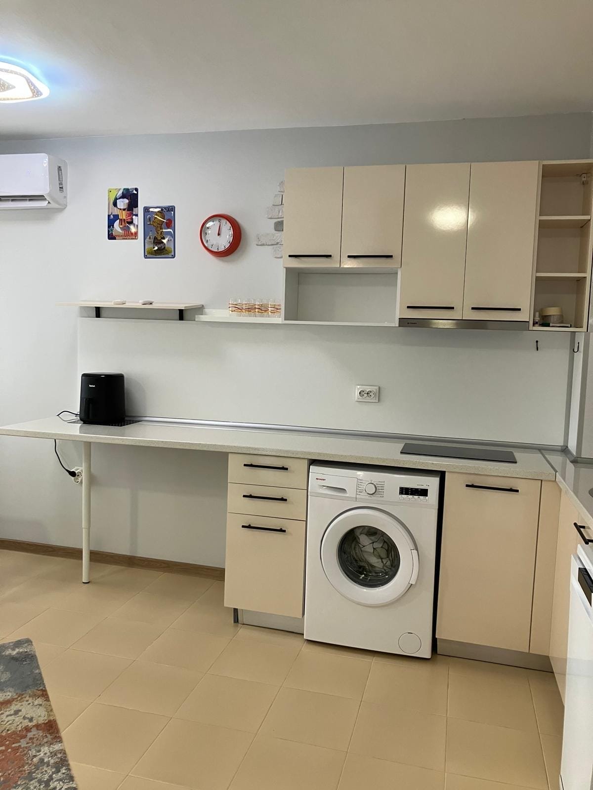 Современная кухня с встроенной техникой, стиральной машиной и функциональными полками, оформленная в светлых тонах.