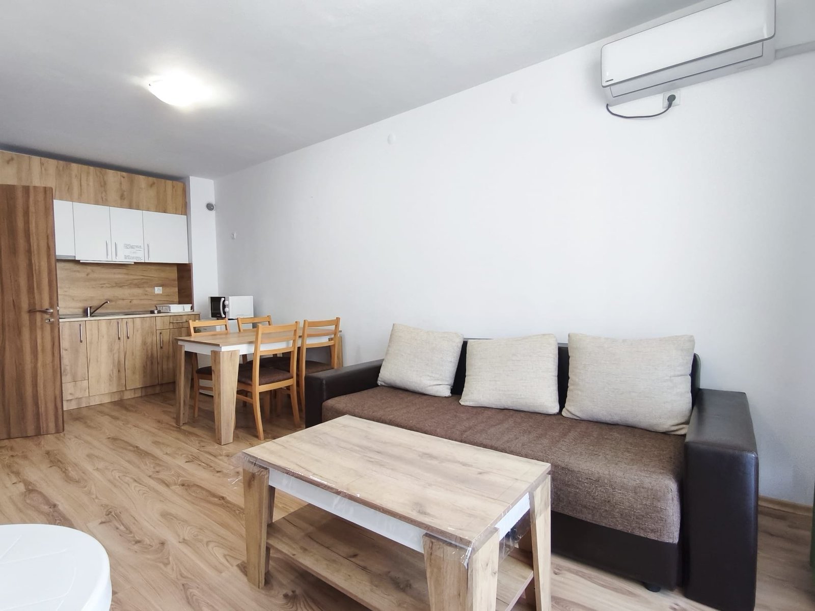 Современная гостиная с диваном и обеденной зоной в квартире Современная квартира в Болгарии с уютной мебелью, светлым интерьером и обеденной зоной для комфортного проживания.