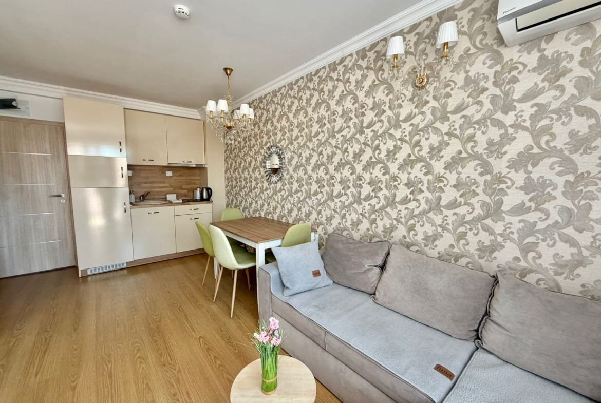 Современная квартира в Болгарии с уютной гостиной, кухней и обеденным столом, оформленная в светлых тонах.