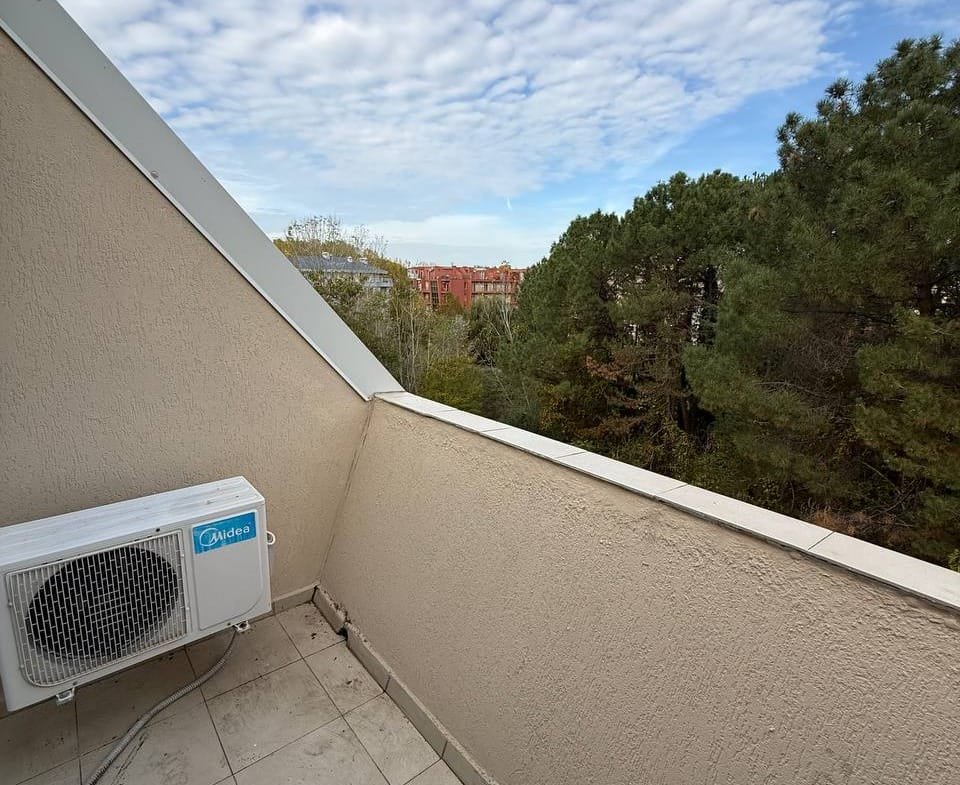 Балкон студии с видом на деревья и облачное небо, расположенный в комплексе Gerber Residence 1.