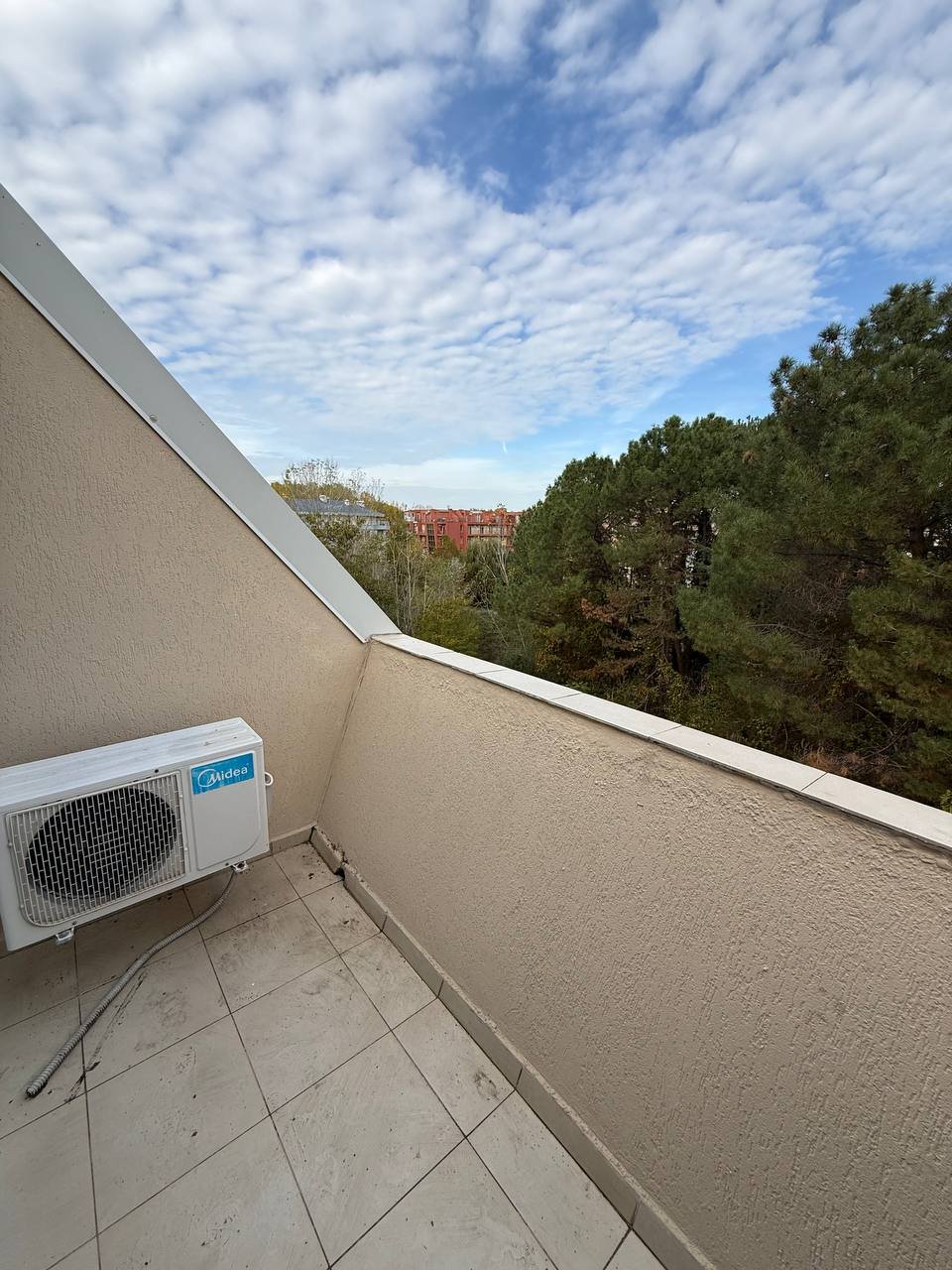 Балкон студии с видом на деревья и облачное небо, расположенный в комплексе Gerber Residence 1.