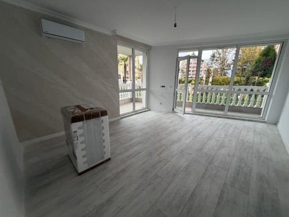 Светлая комната с большим окном, белыми стенами и светлым полом, готовая для продажи недвижимости в Болгарии.