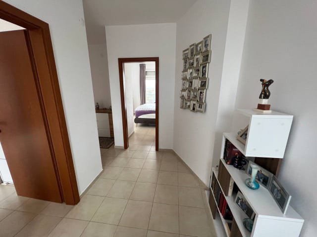 Современный коридор квартиры в Болгарии с фотографиями на стене и выходом в спальню. Светлые тона и лаконичный интерьер.