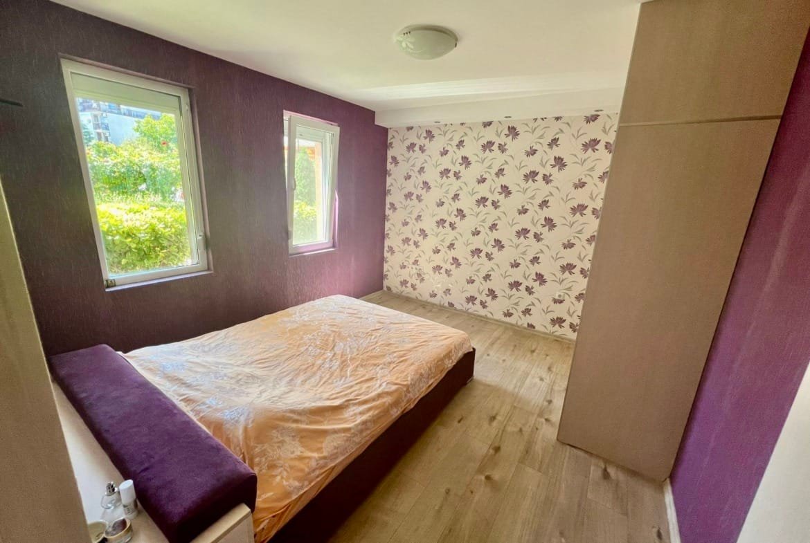 Современная спальня с светлыми стенами, напольным покрытием и односпальной кроватью, предлагающая комфорт для покупки недвижимости в Болгарии.