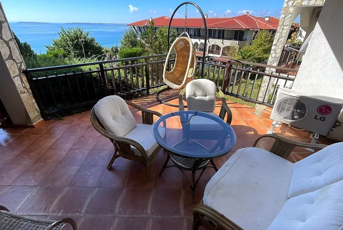 Уютная веранда с креслом-качалкой и столом, с видом на море, привлекает покупателей недвижимости в Болгарии.