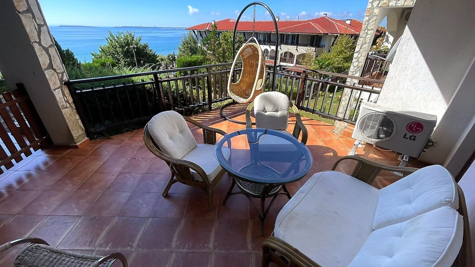 Уютная веранда с креслом-качалкой и столом, с видом на море, привлекает покупателей недвижимости в Болгарии.