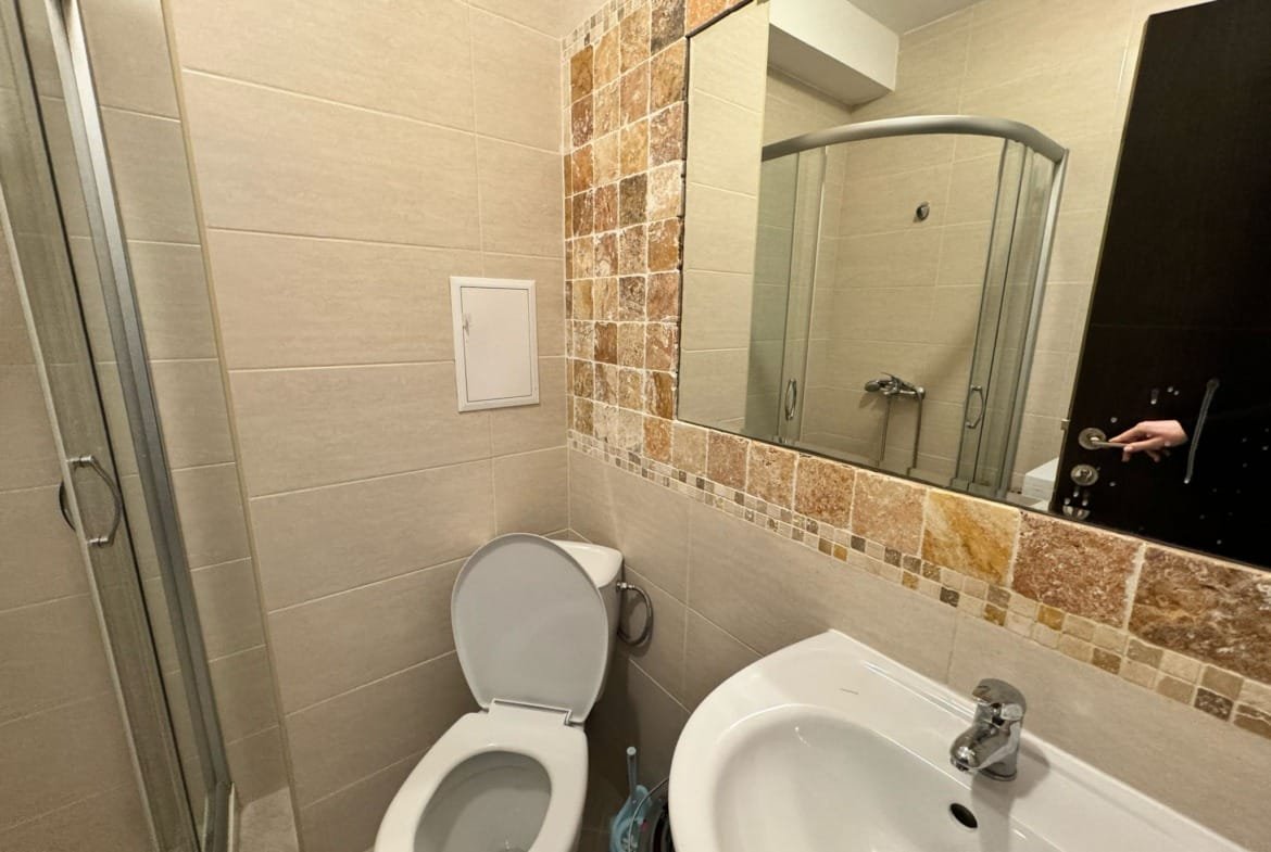 Современный санузел с душевой кабиной, унитазом и раковиной, оформленный в светлых тонах для продажи недвижимости в Болгарии.