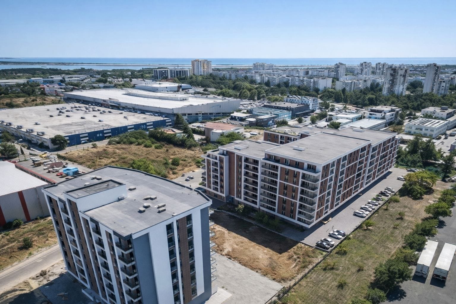 Современные жилые комплексы и городская инфраструктура возле берега. Новые жилые комплексы в Болгарии, рядом с морем, на фоне городской застройки и зеленых насаждений.