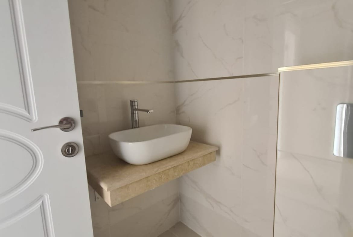 Современная ванная комната в Болгарии с минималистичным дизайном, раковиной на мраморной столешнице и плиткой светлых тонов.