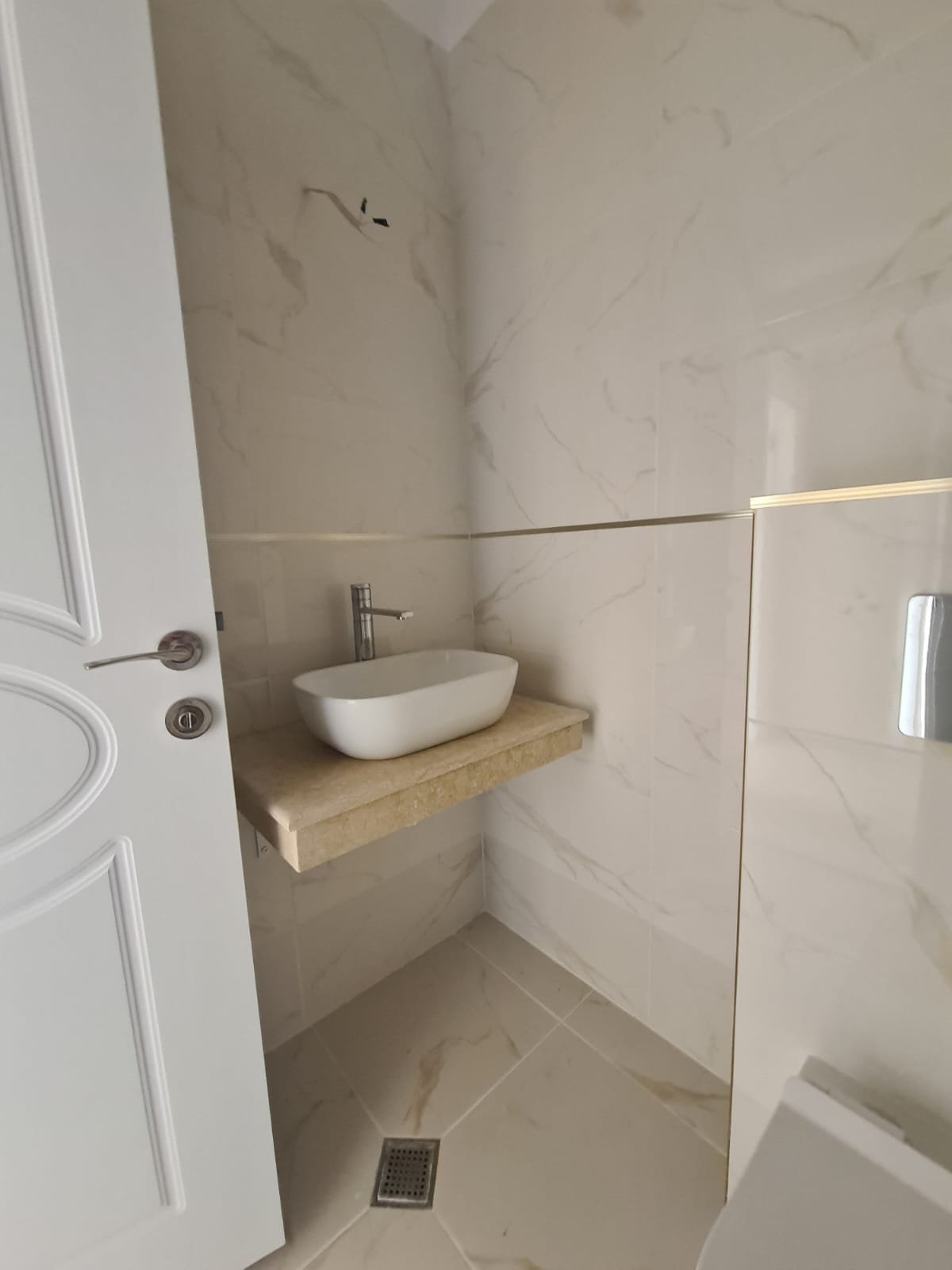 Современная ванная комната в Болгарии с минималистичным дизайном, раковиной на мраморной столешнице и плиткой светлых тонов.