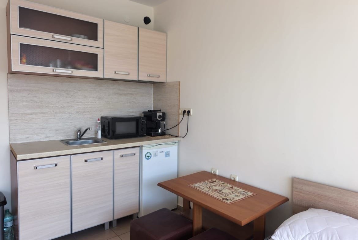 Современная кухня с минималистичной мебелью, встроенной техникой и обеденным столом, подходит для жизни в Болгарии.