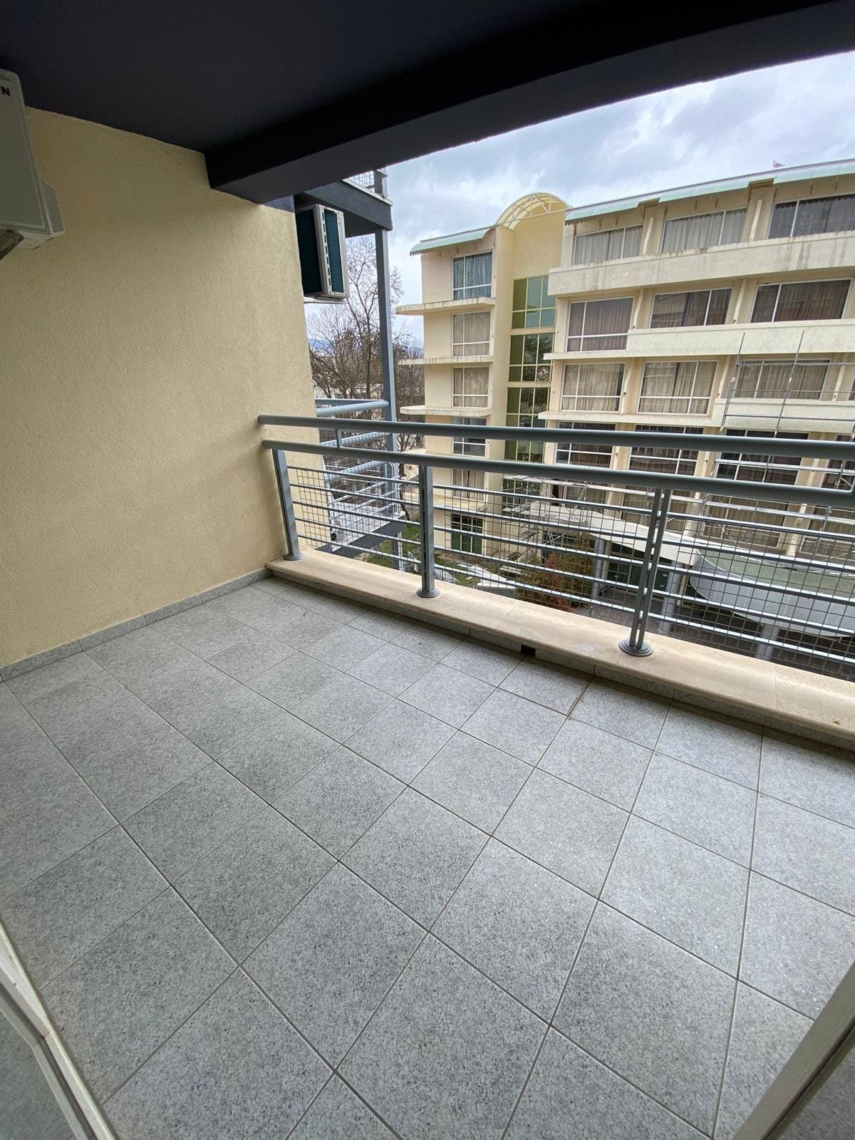 Пустой балкон с плиточным покрытием, панорамным видом на жилой дом в Болгарии, идеальное место для отдыха и покупок недвижимости.