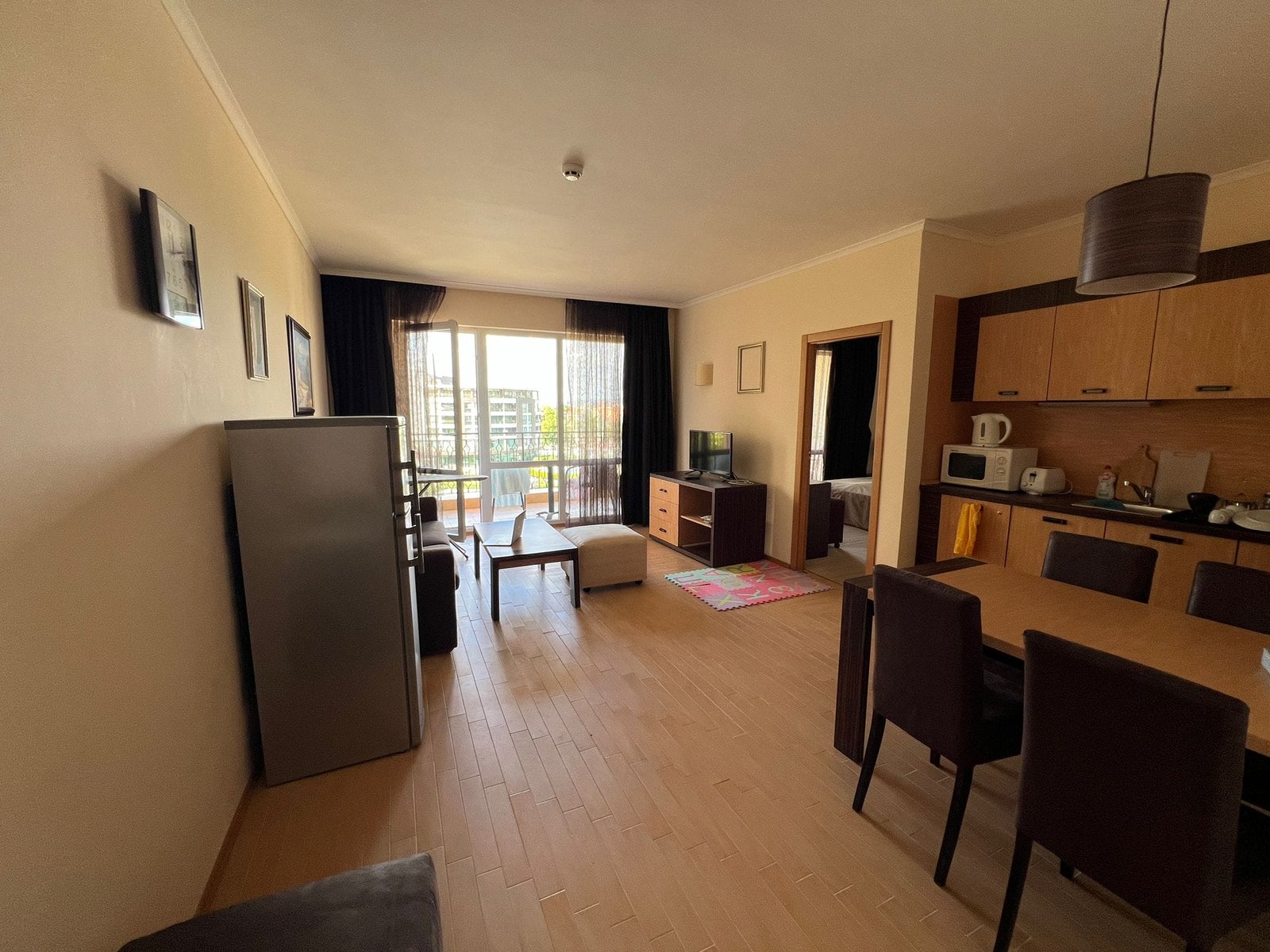 Современная квартира-студия с кухней и балконом в интерьере. Современная квартира в Болгарии с кухней, обеденным столом и балконом, указывающим на комфорт и уют для покупки или аренды.