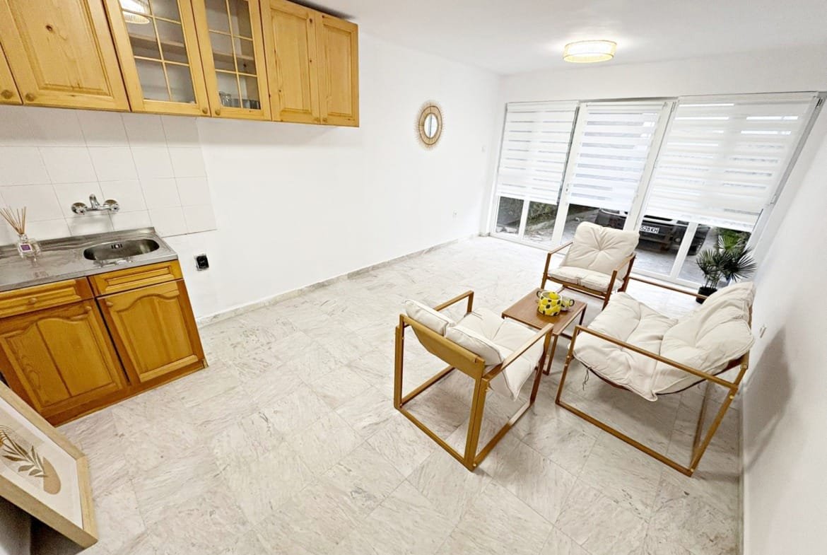 Светлая квартира с кухонным уголком, диваном и большими окнами, готовая для продажи в Болгарии.