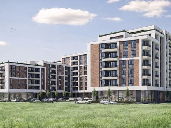 Современный жилой комплекс с кирпичными фасадами, зелеными террасами и парковкой на фоне голубого неба в Болгарии.