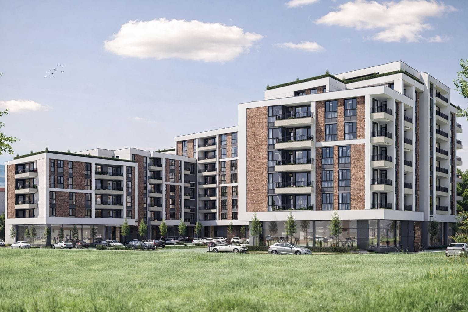 Современный жилой комплекс с кирпичными фасадами, зелеными террасами и парковкой на фоне голубого неба в Болгарии.