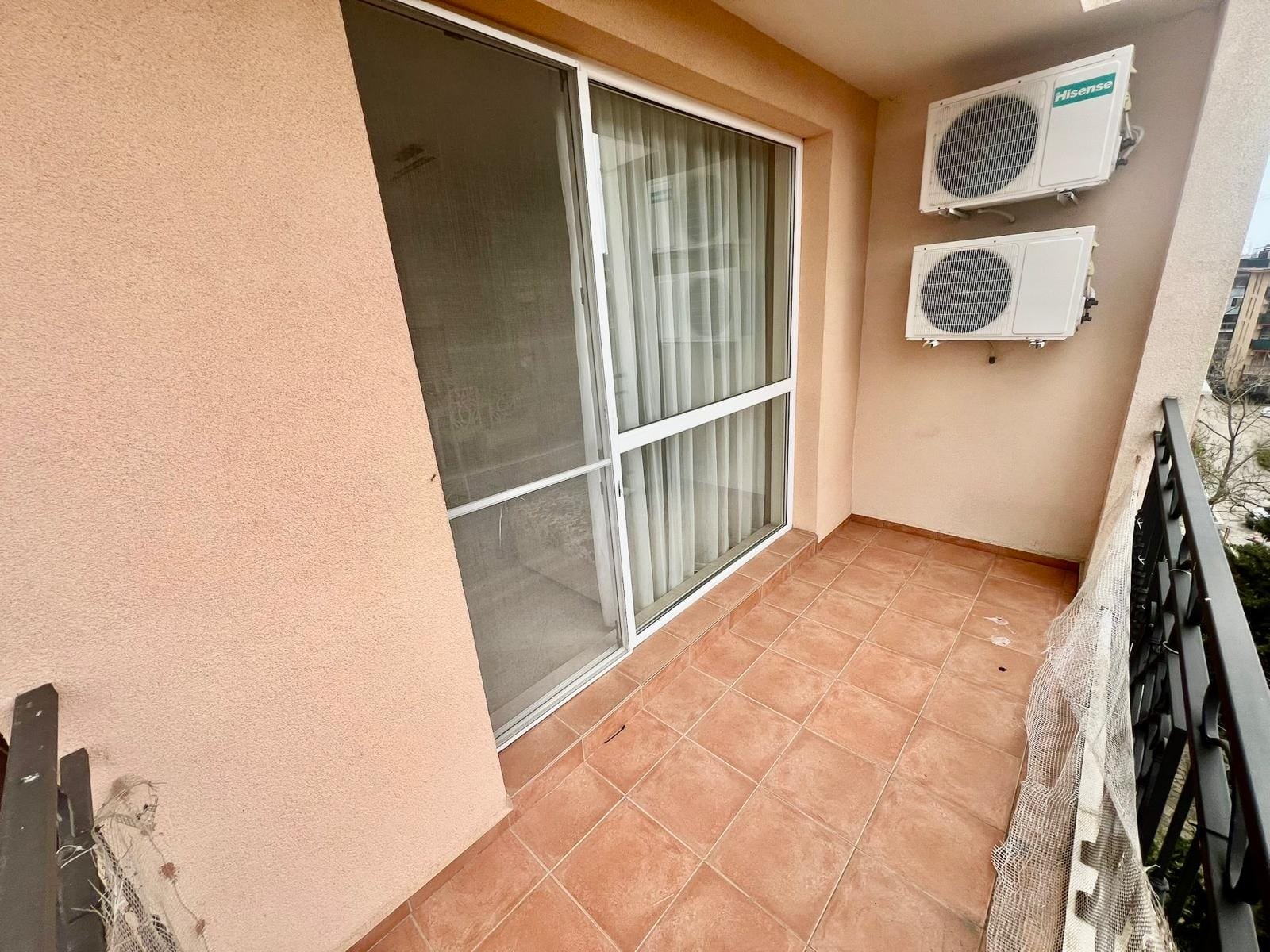 Балкон с плиточным полом, стеклянными дверями и кондиционерами, идеальный для покупки недвижимости в Болгарии.