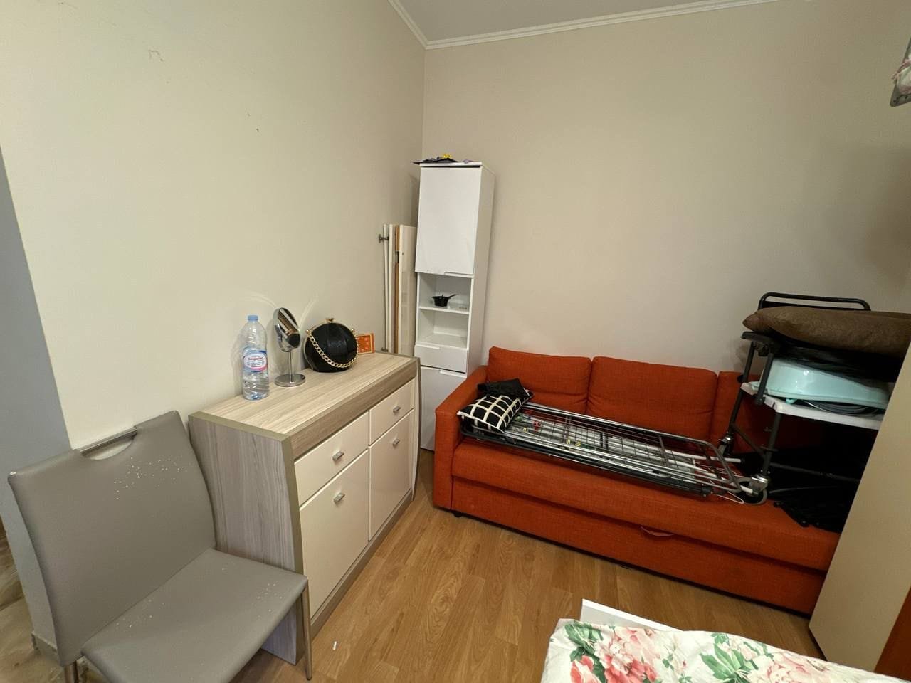 Уютная комната с диваном и шкафом для хранения вещей Уютная комната с оранжевым диваном, тумбой и зеркалом, идеально подходит для продажи или аренды недвижимости в Болгарии.