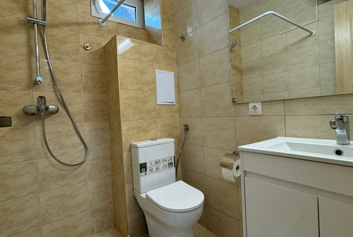 Светлая ванная комната с душевой кабиной, унитазом и современной сантехникой, подходящая для продажи недвижимости в Болгарии.