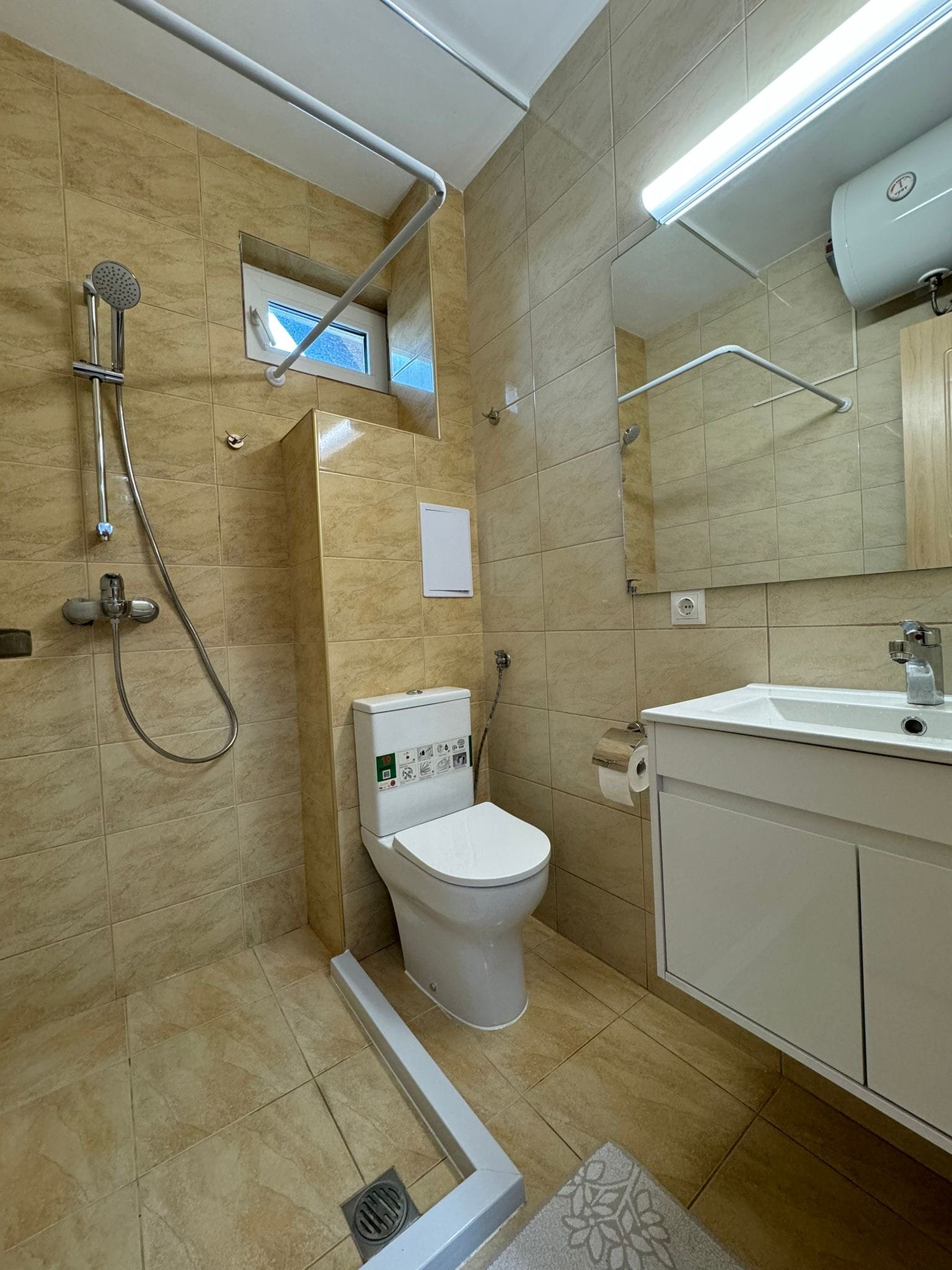 Современная ванная комната с душем и туалетом в светлых тонах Светлая ванная комната с душевой кабиной, унитазом и современной сантехникой, подходящая для продажи недвижимости в Болгарии.