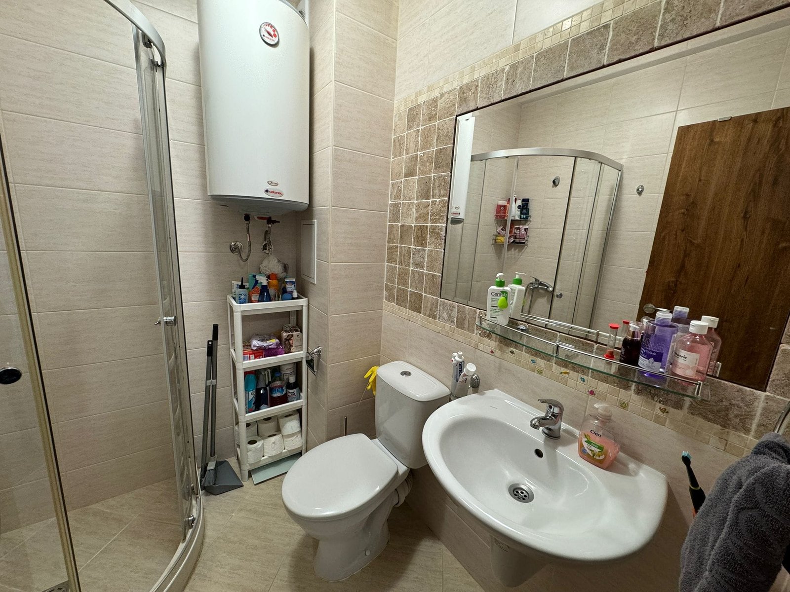 Современный санузел с душевой кабиной и полками для хранения Современная ванная комната с душевой кабиной, умывальником, туалетом и полками для косметических средств.