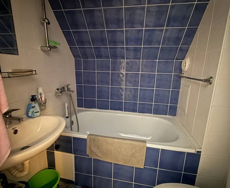 Современная ванная комната с угловой ванной, умывальником и туалетом, отделка в синих и белых тонах.