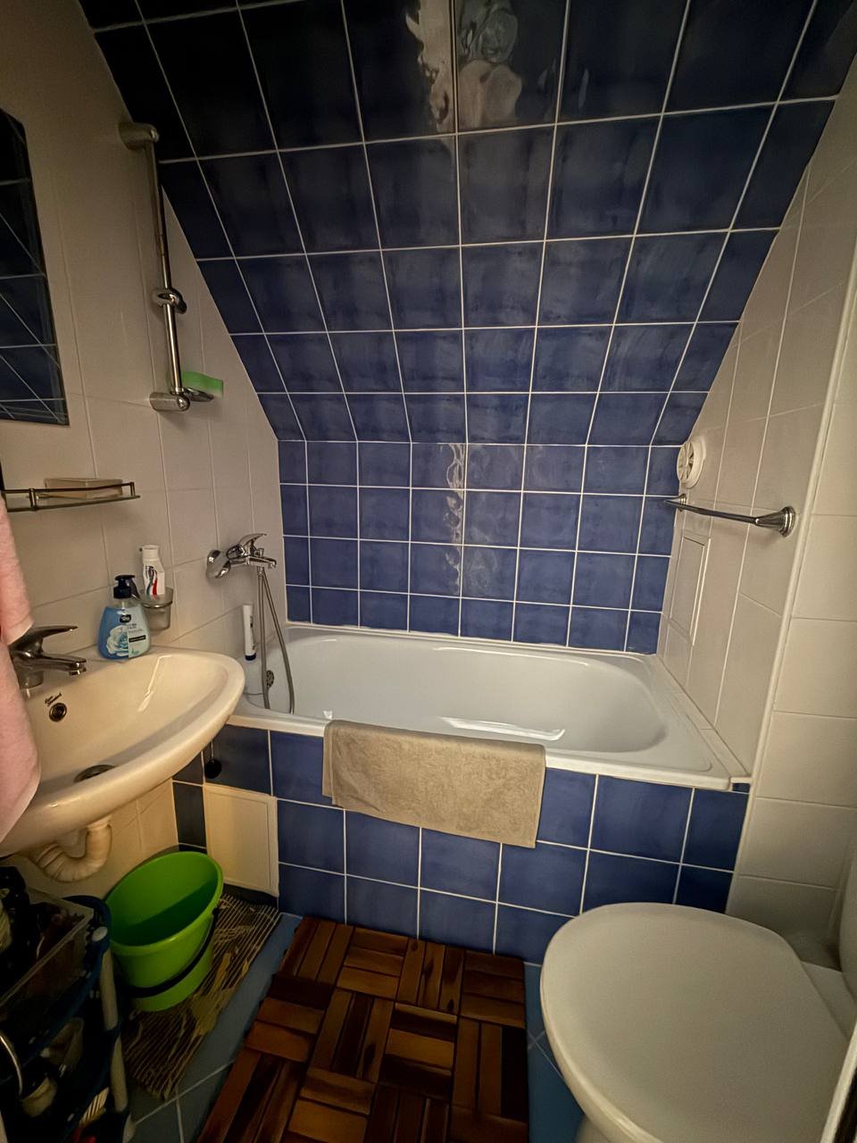 Современная ванная комната с угловой ванной, умывальником и туалетом, отделка в синих и белых тонах.