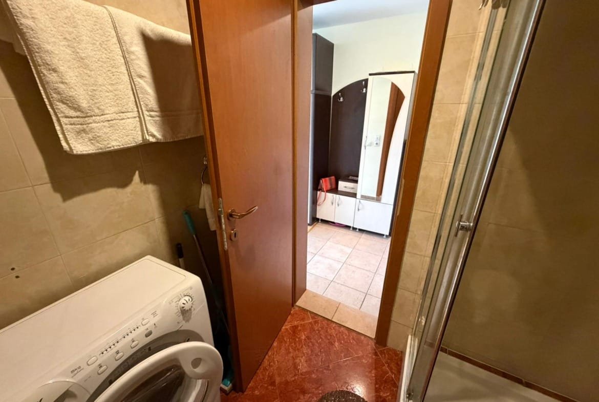 Современная ванная комната с душевой кабиной, стиральной машиной и плиткой, идеальна для покупки недвижимости в Болгарии.