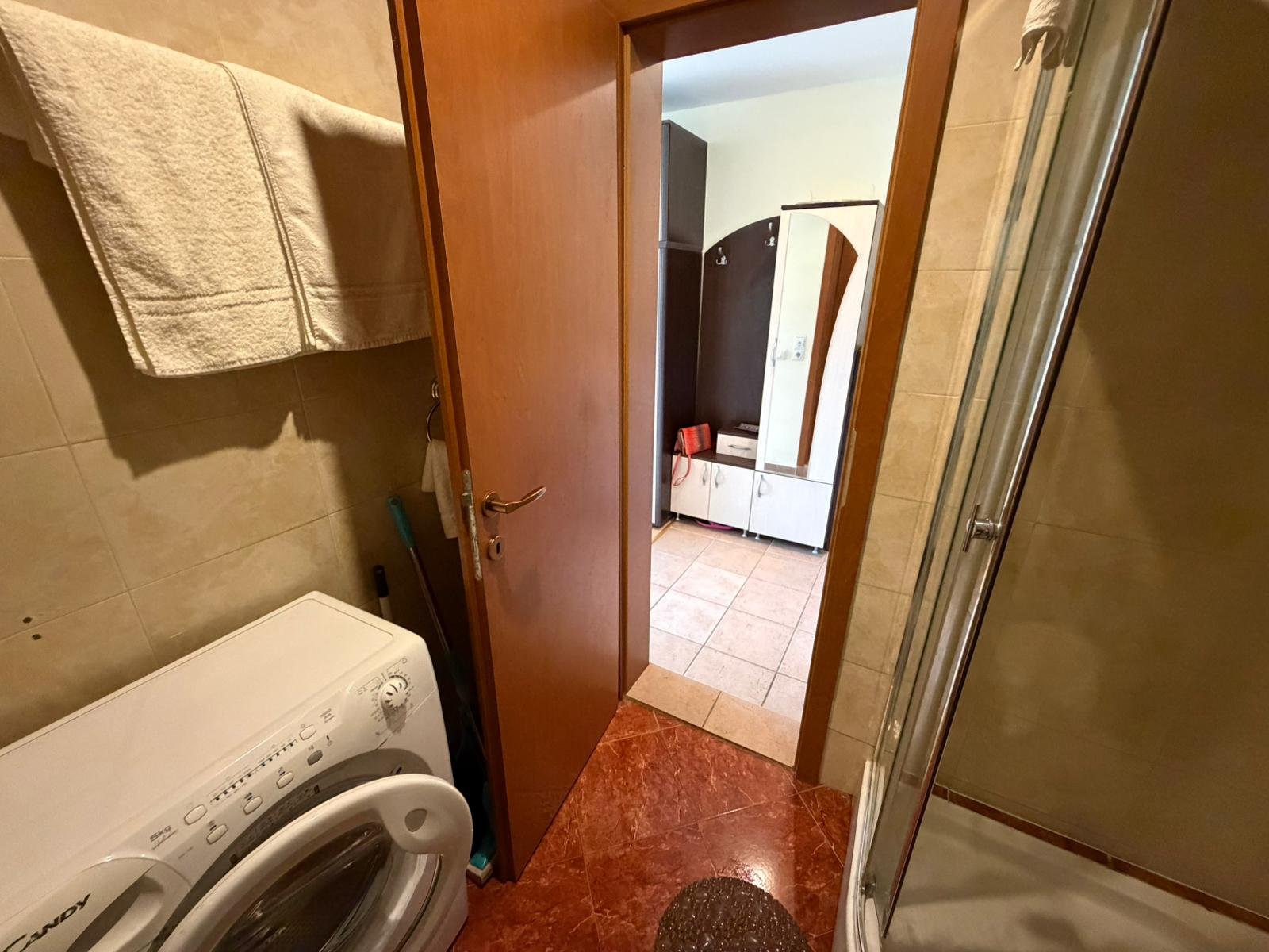 Ванная комната с стиральной машиной и душевой кабиной Современная ванная комната с душевой кабиной, стиральной машиной и плиткой, идеальна для покупки недвижимости в Болгарии.