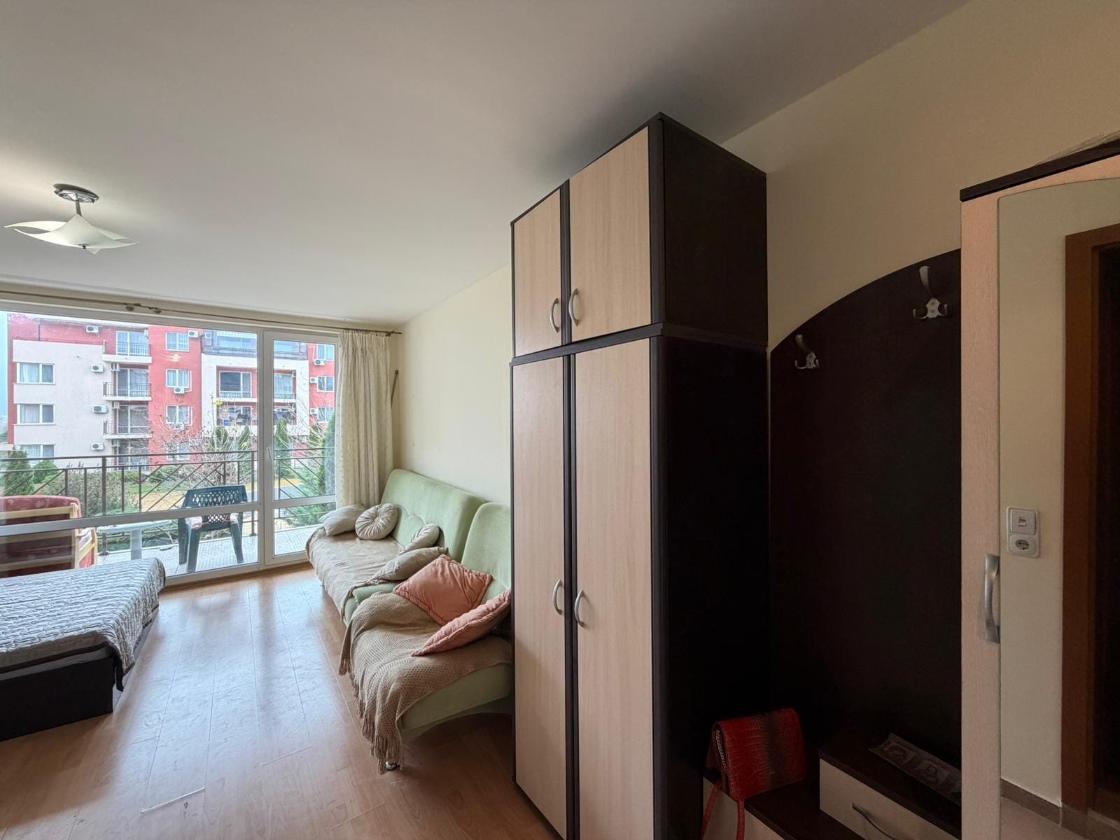 Современный интерьер квартиры с балконом и уютной мебелью Современная квартира в Болгарии с мебелью, светлыми стенами и панорамным окном, создающим уютную атмосферу.