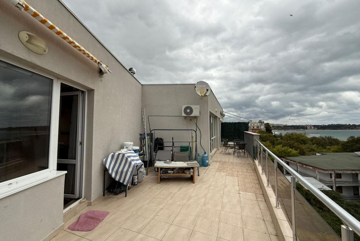 Терраса с шикарным видом на море в Болгарии, оборудованная мебелью и зоной для отдыха, идеальна для покупки недвижимости.