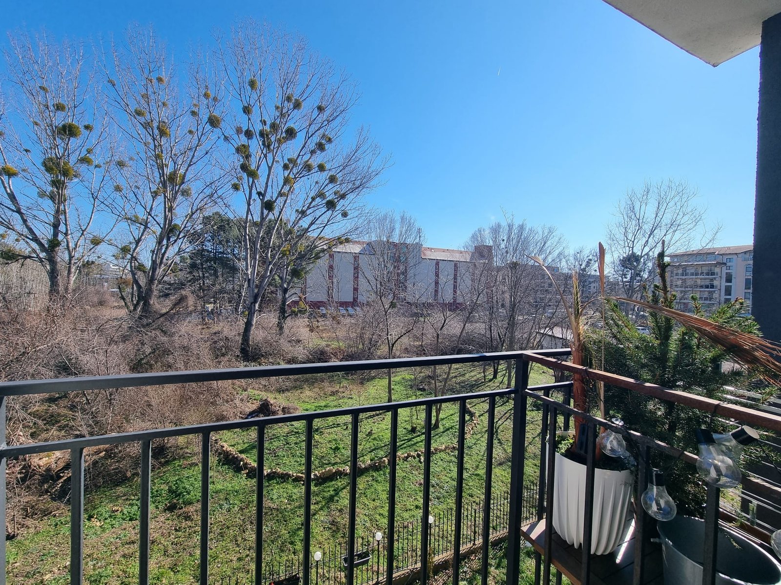 Вид с балкона на зелёный ландшафт и здания в Болгарии, идеальное место для покупки недвижимости у природы.