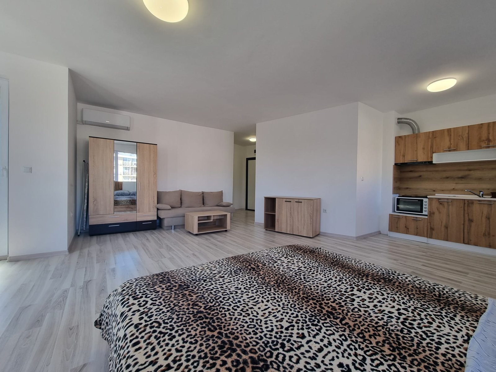 Современная квартира в Болгарии с деревянной мебелью, светлыми стенами и открытым пространством для комфортного проживания.