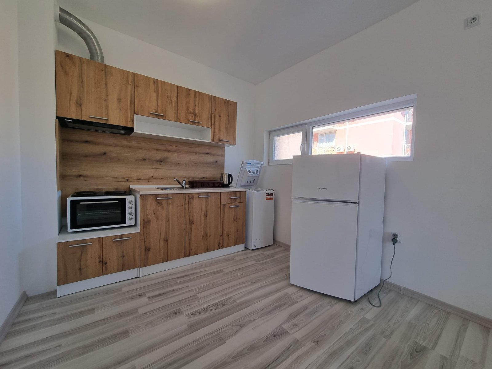 Современная кухня с деревянными фасадами, холодильником и микроволновой печью, идеальная для продажи недвижимости в Болгарии.